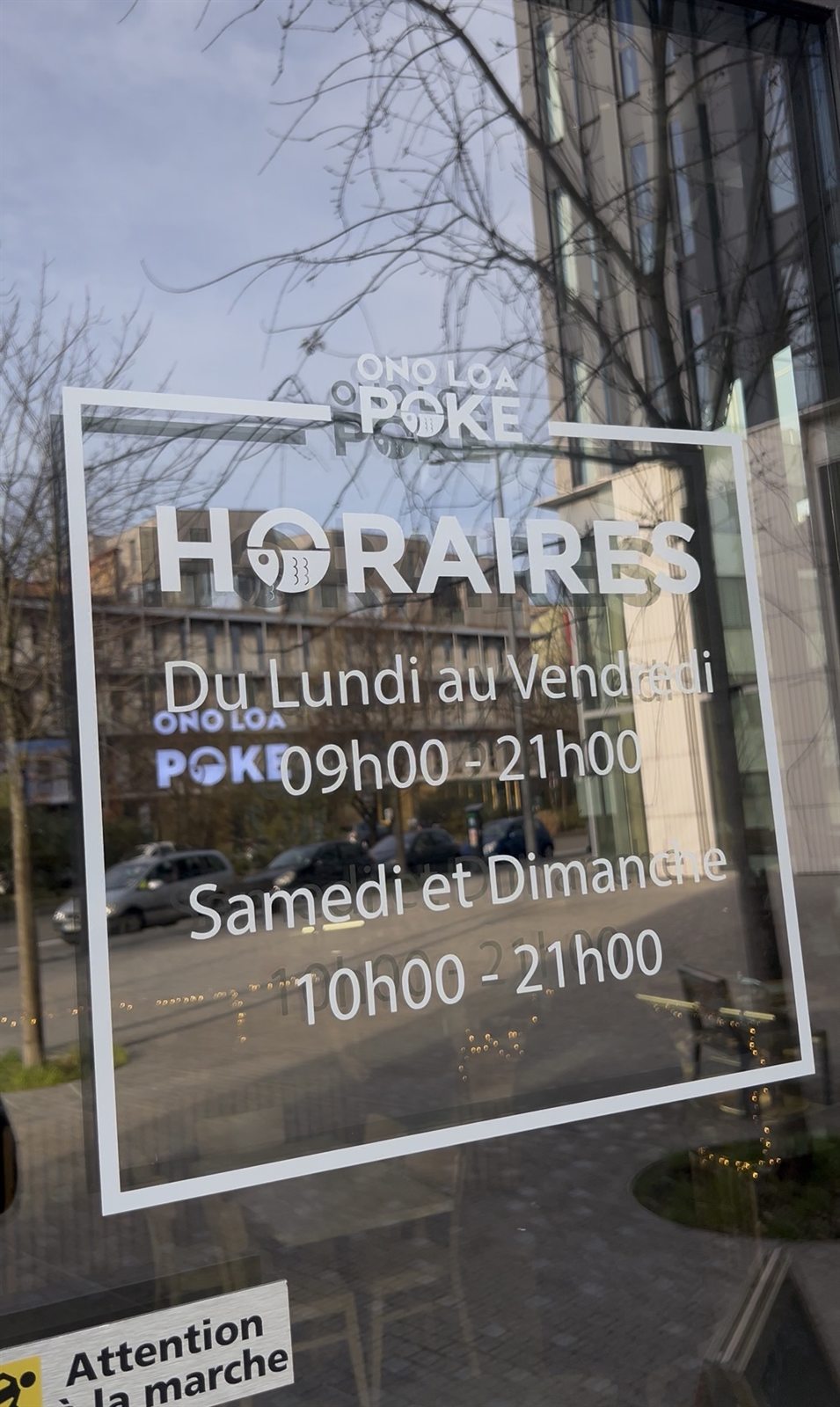 Lettrage et horaires appliqués sur une vitrine de salon